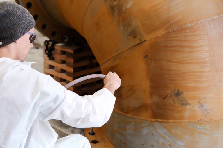 Applicator spraying a protective coating on a steel structure